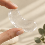 Close-up of a hydrating gel eye patch held between two fingers